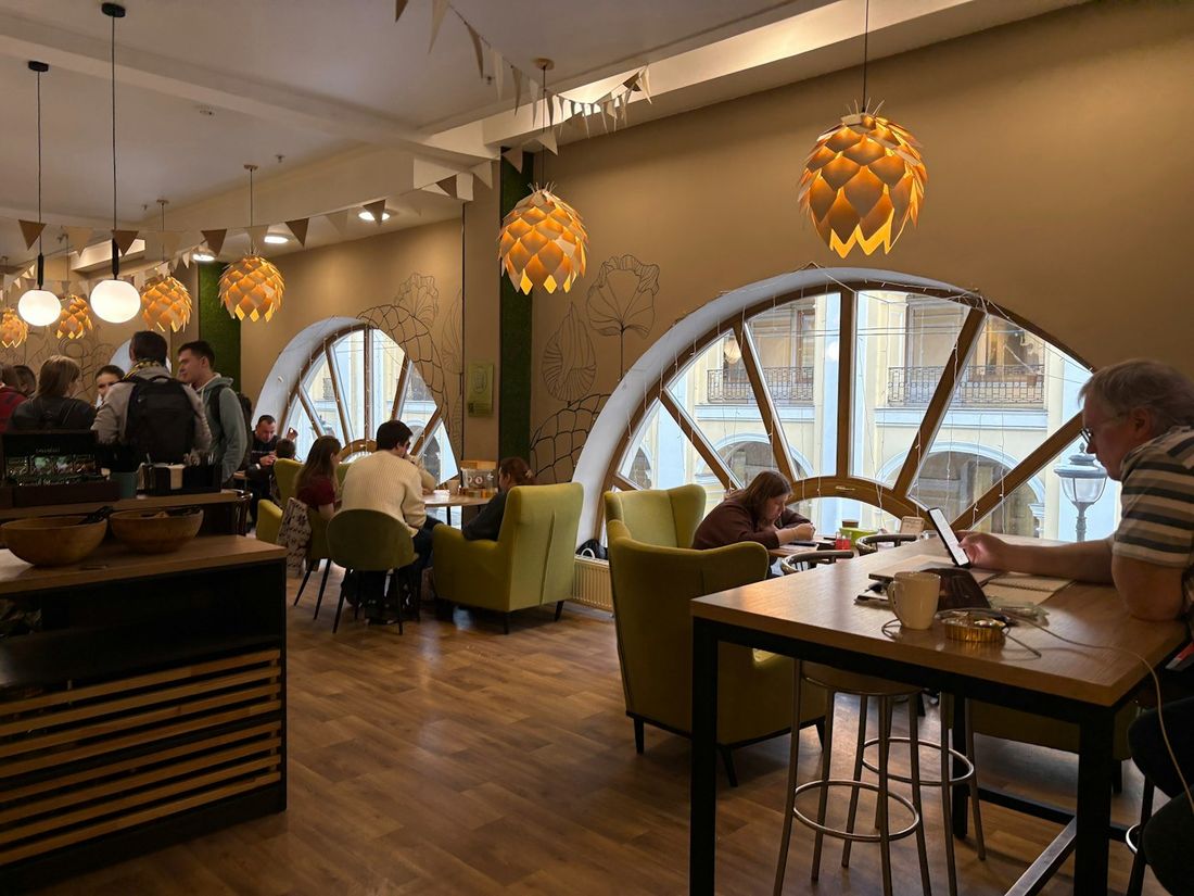 Cafetería acogedora con sillones, lámparas cálidas y ventanales en arco