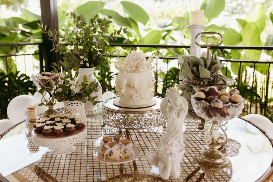 Mesa de postres decorada con una torta blanca, bombones y flores